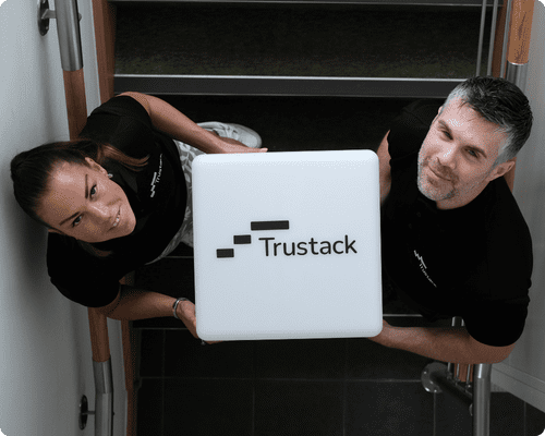 Two members of the Trustack team holding a large cube bearing the Trustack logo